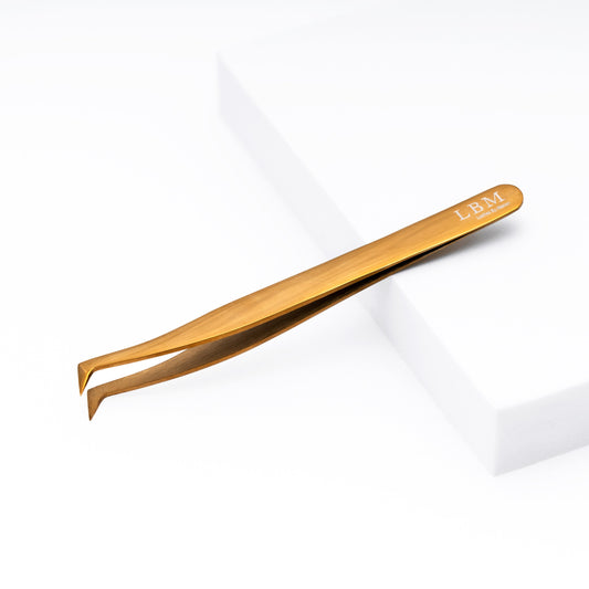 Gold-colored tweezers with 'LBM' branding on a white background