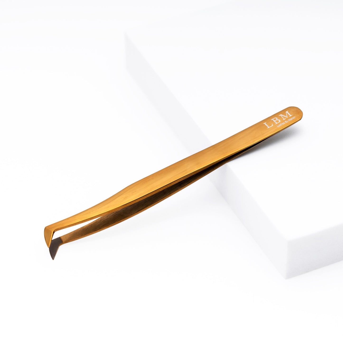Gold-colored tweezer with 'LBM' branding on a white background