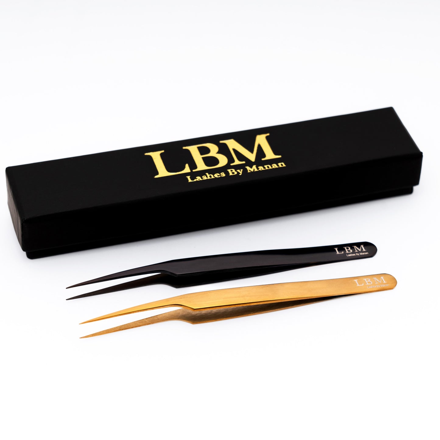 Pair of eyelash tweezers with a black box labeled 'Lashes By Manan' on a white background