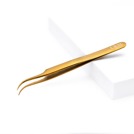 Gold-colored tweezers on a white background