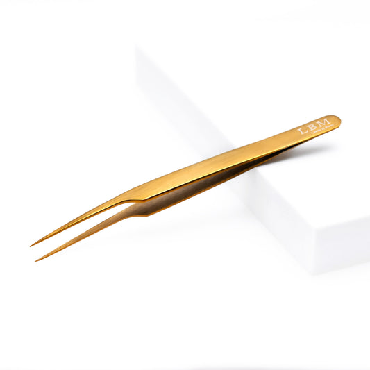 Gold-colored tweezers with 'LBM' branding on a white background