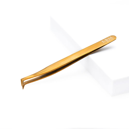 Gold-colored tweezers on a white background